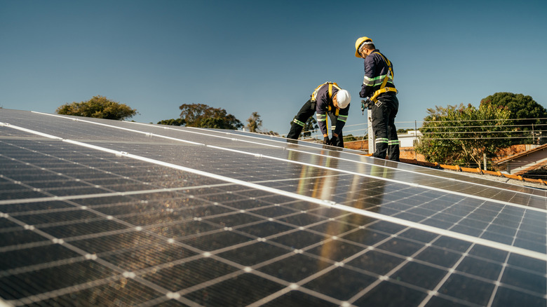 two workers installing solar panels on a roof