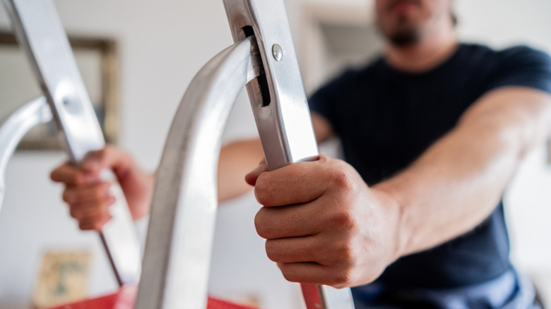 Close up of a man climbing a step ladder