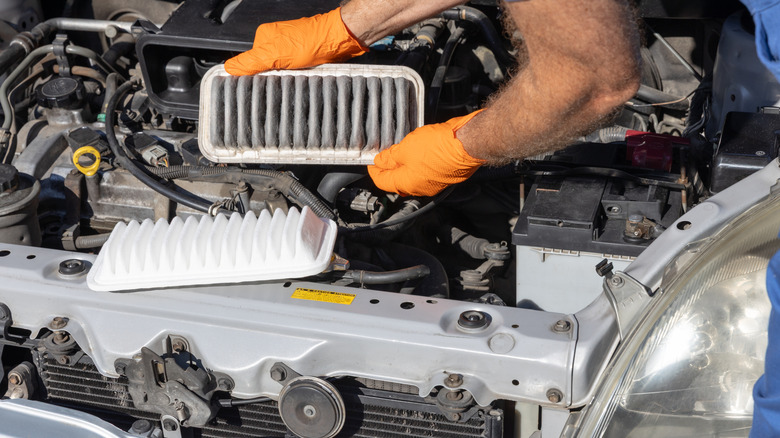 A person changing dirty engine air filter