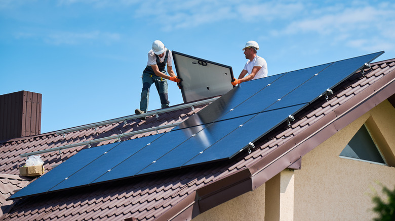 Installers fitting solar panels to a house's roof