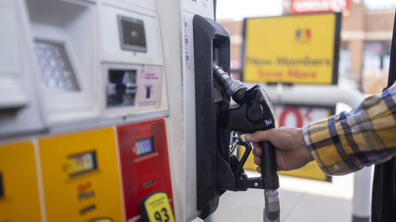 A man wearing a flannel shirt reaches for a pump handle