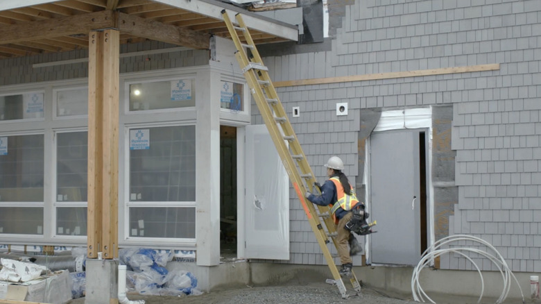 A woman climbs a step ladder at a construction site