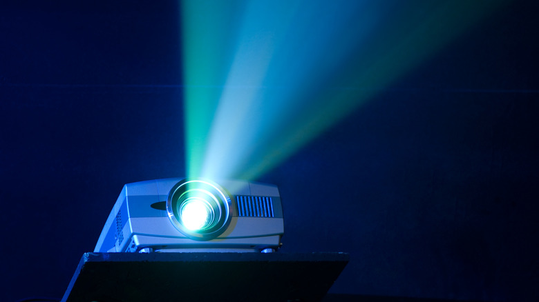 Light beams emitting from a projector lens in a dark room.