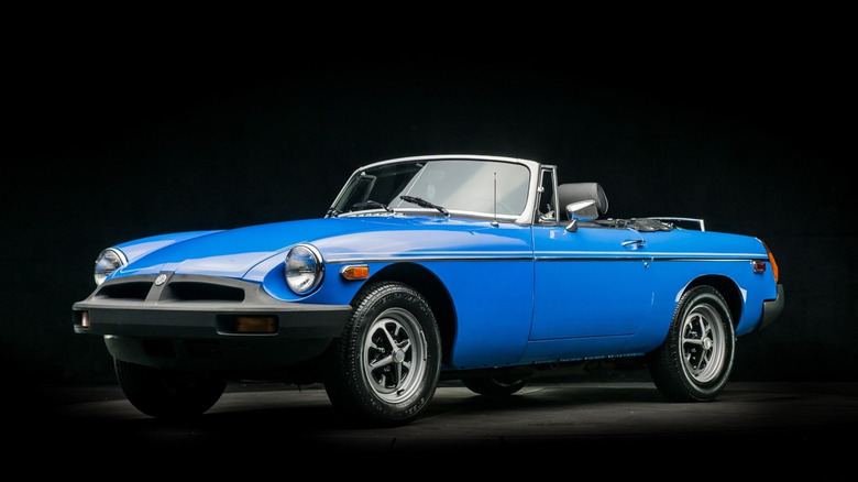 Front 3/4 view of a blue MGB with rubber bumpers, roof down