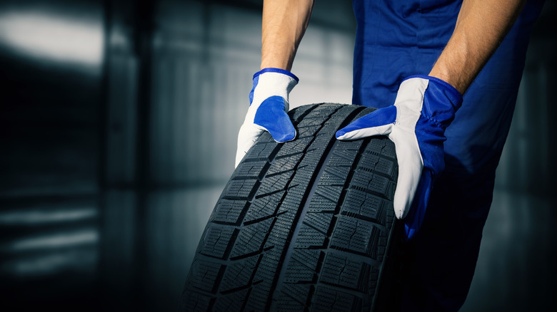 New tire being rolled by gloved person