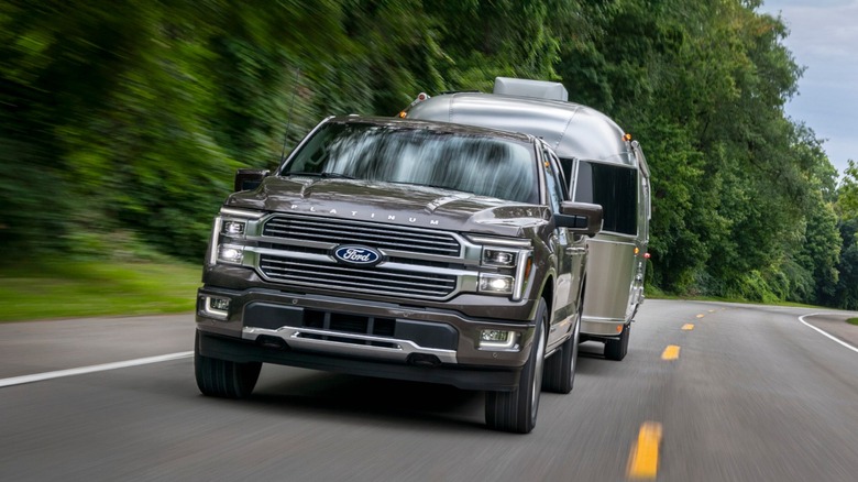 Head-on view of Ford F-150 towing a travel trailer on a rural road.