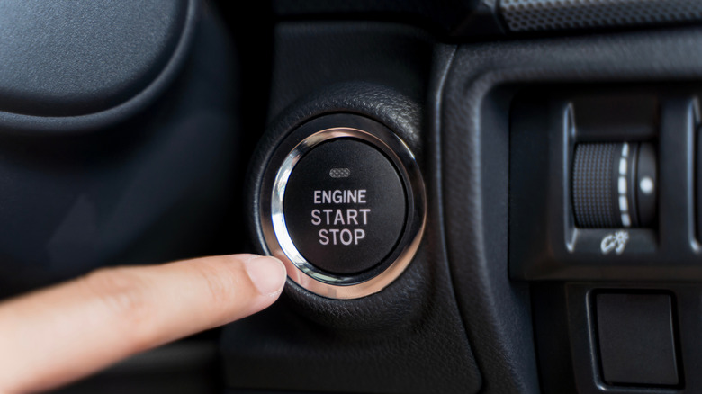 Close up of a finger pushing a start/stop engine button in a car
