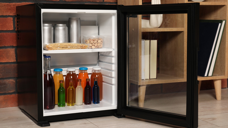 An open mini fridge full of bottles and containers.
