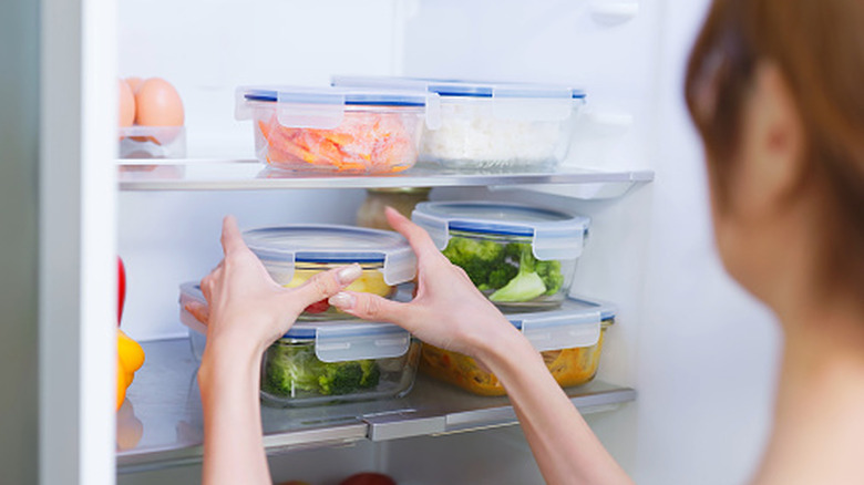 A lady taking cooked food from the refrigerator