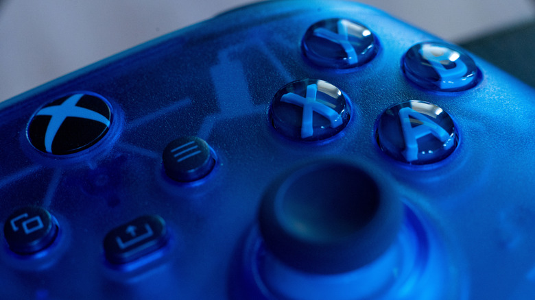 The joystick and buttons on a blue Xbox controller.