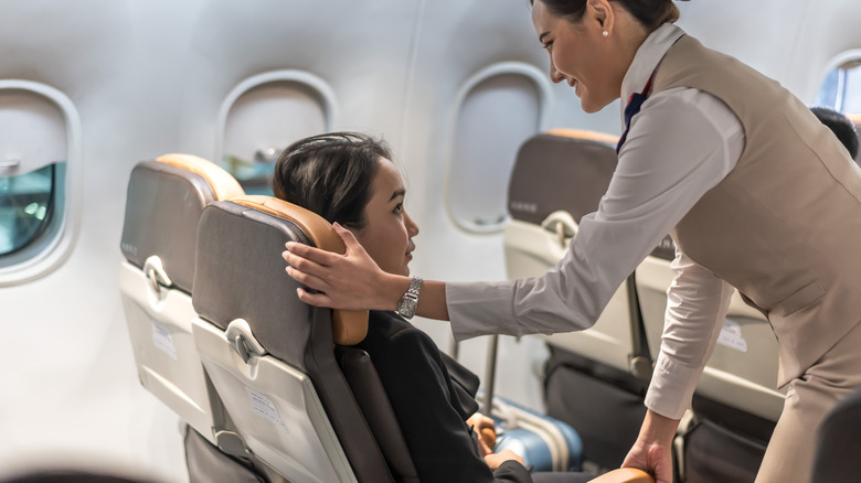 Female air hostess adjusting the seat of a passenger