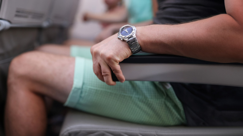 A man sitting on the plane seat and strongly grabbing the armrest