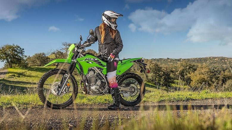 Person riding a green Kawasaki KLX 230S in grass
