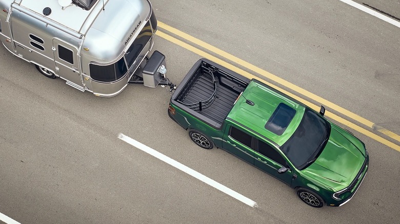 A green Ford Maverick towing a trailer