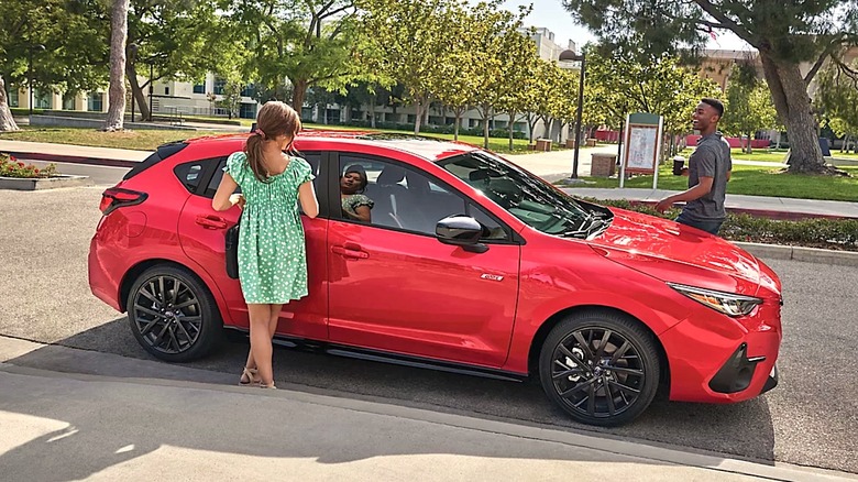 People getting into a red Subaru Impreza