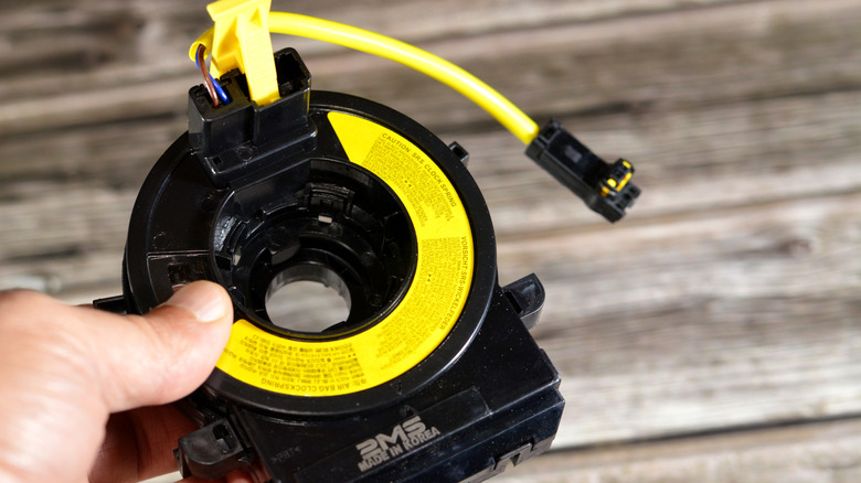 Hand holding clock spring for steering wheel
