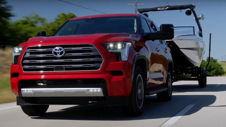 Red Toyota Tundra pickup truck towing a trailer on the highway