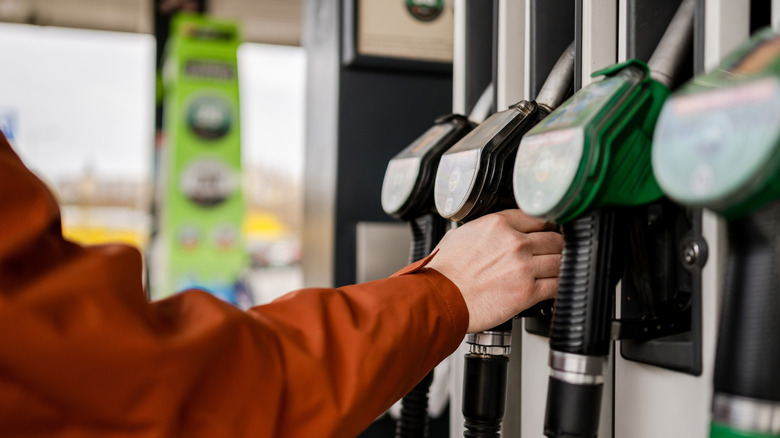 Man grabbing a fuel pump at a gas station