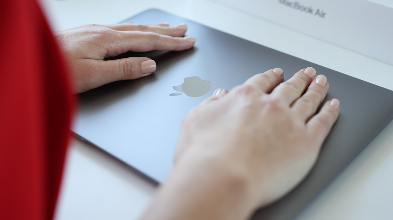 woman's hands over closed MacBook
