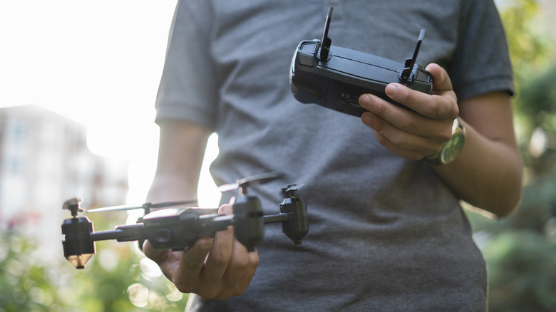 A young made holding a drone and the the remote controller for it.