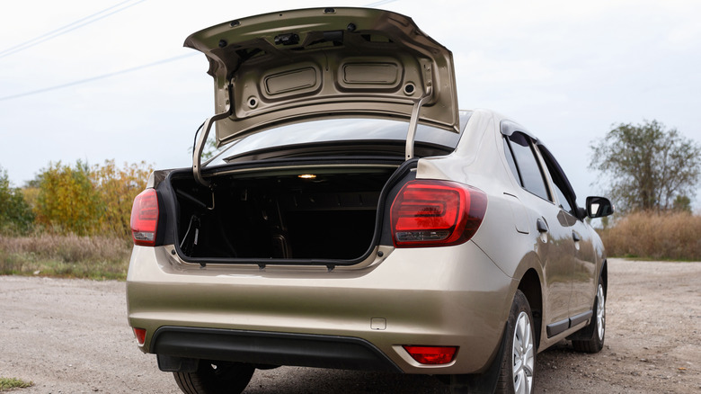 The open trunk of a gold Renault Logan, rear 3/4 view