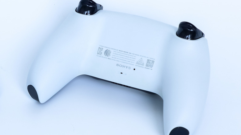 A PS5 controller on a white surface.