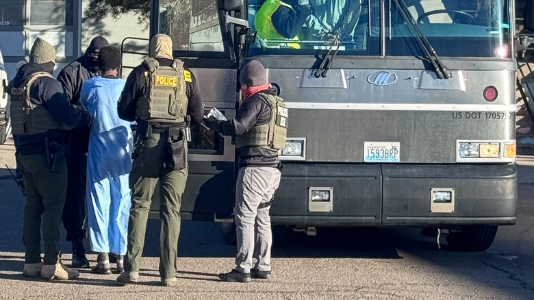 ICE agents moving people onto a bus