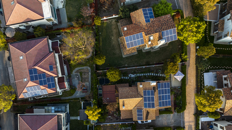 Aerial photo of several rooftops with solar panels.