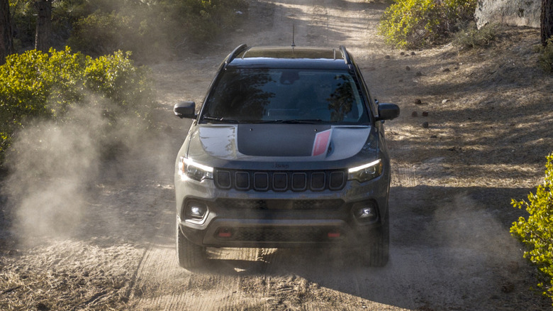 Front view of grey Jeep Compass on dusty forest dirt road