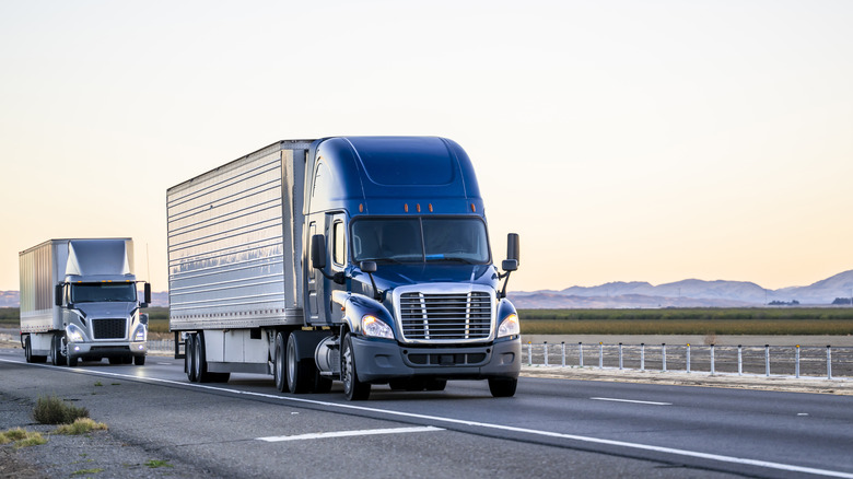 Two semi-trucks driving down freeway