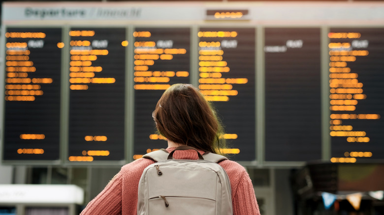 Woman in front of Airport flight schedule board