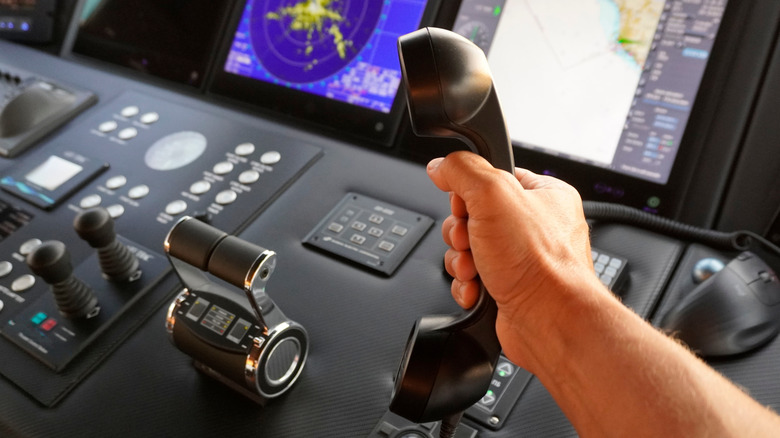 Hand holds phone above ship's navigation dashboard