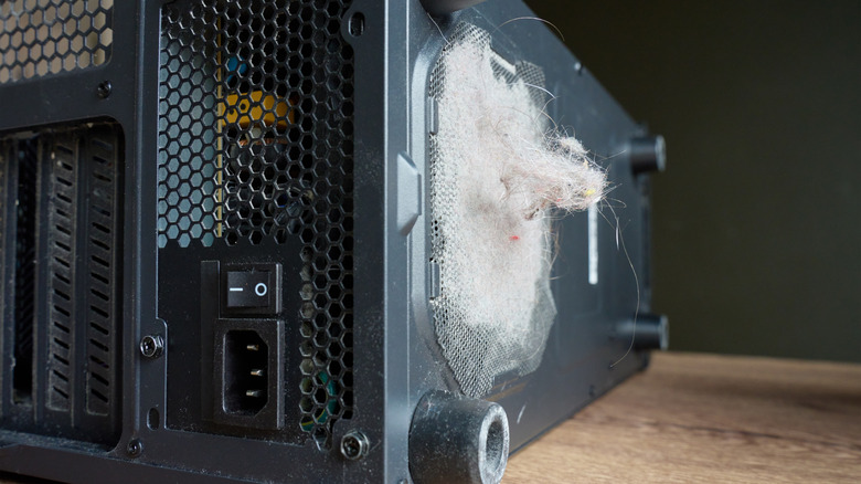 An image of a PC case on it's side, showing the PSU intake fan clogged with dust and hair