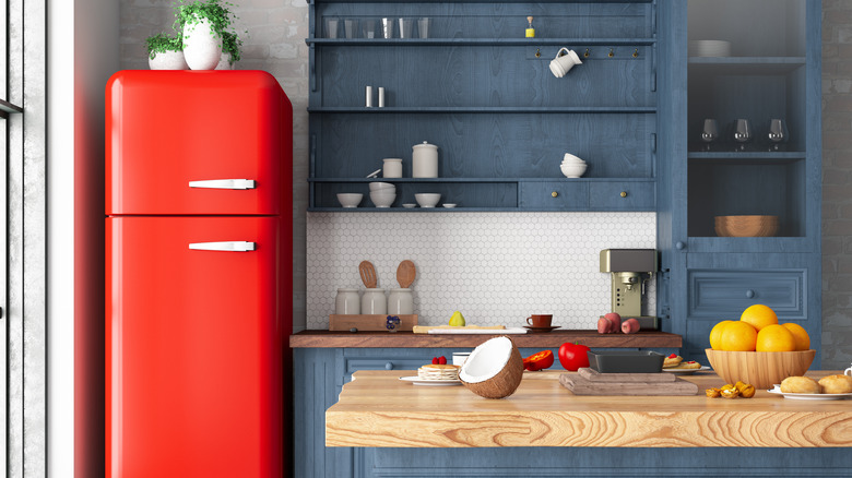 A red refrigerator in the corner of a kitchen.