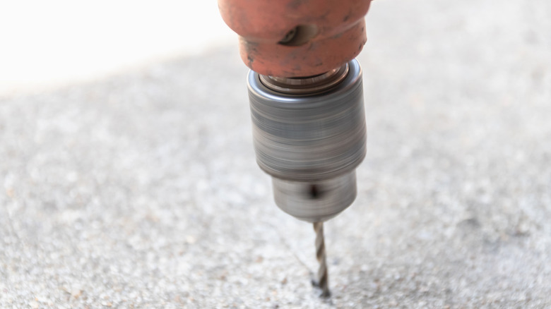 A rotary drill bit boring into concrete