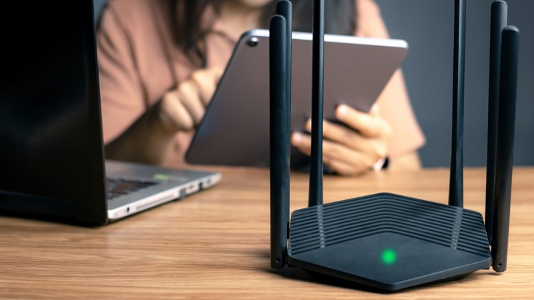 black router with green LED light and girl with tablet