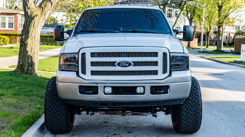 A front end view of a white 2008 Ford F250 parked on a suburban street.