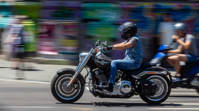 A dynamic photo of a man riding a Harley-Davidson Fat Boy through urban streets.