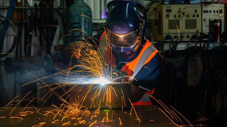 Industrial welder working at workshop with a safety vest