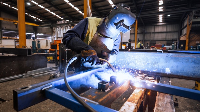 A welder with protective gear welding steel bars
