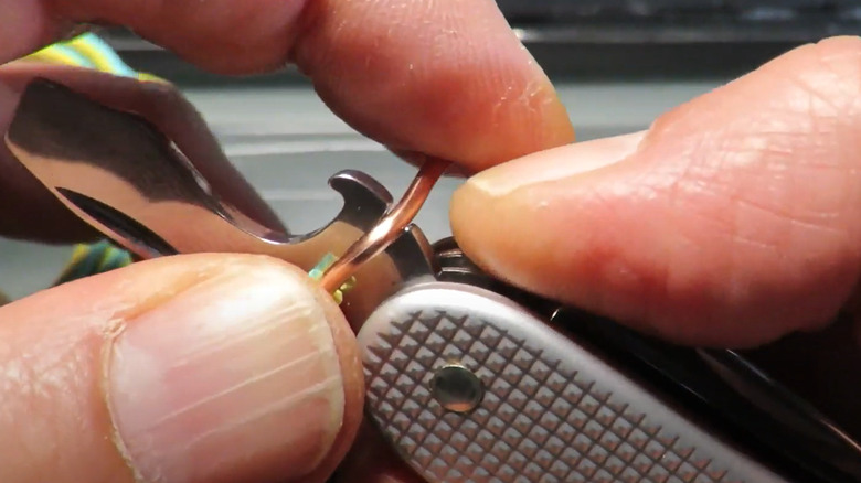 Image of a man using the wire stripping tool on a Swiss Army knife