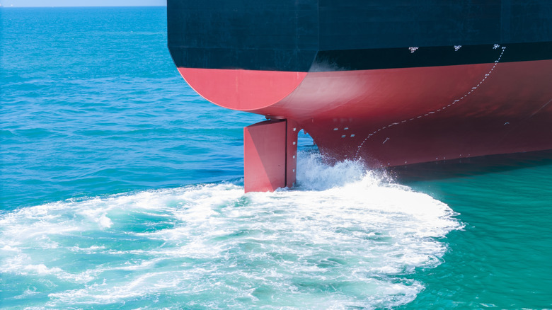 Propeller of large ship spinning power working and water splash contrail