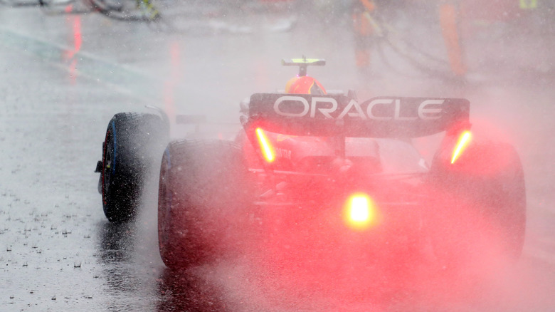 Red Bull F1 car from behind in rain in pit lane with red light lit