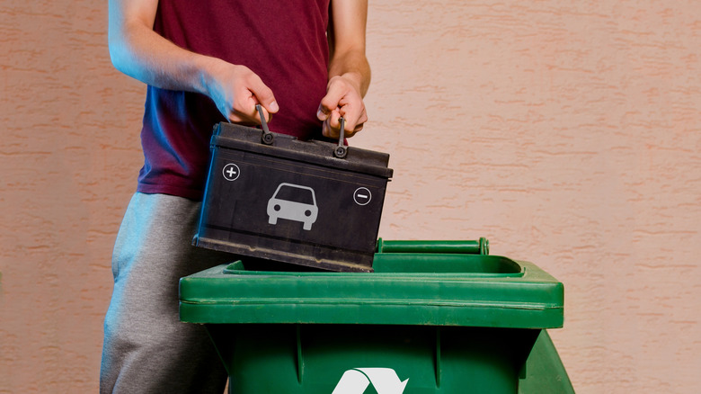 Man throwing car battery in recycling bin