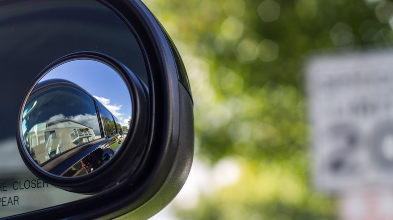 Close up of a blind spot mirror on the passenger side with a blurred background