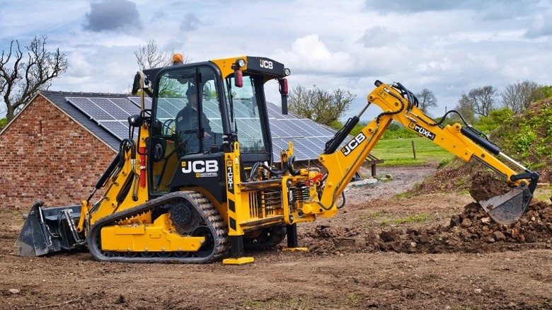 A JCB 1CXT Track Loader scooping up dirt