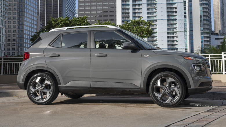 Side profile of a parked 2025 Hyundai Venue with high-rise buildings in the background