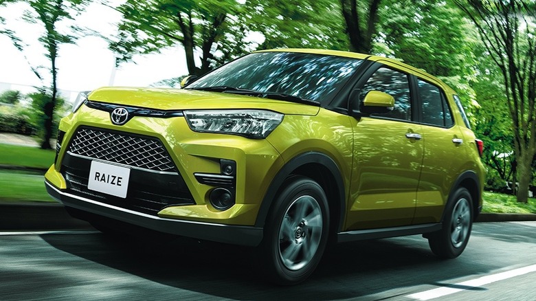 Toyota Raize driving on a road with trees in the background
