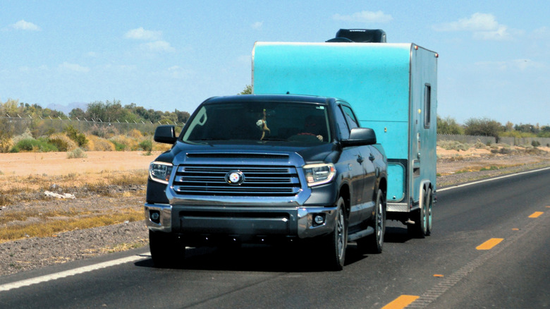 A Toyota Tundra pickup truck tows a custom turquoise tandem-axle box trailer