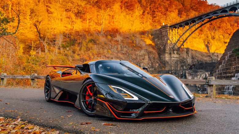 SSC Tuatara Striker parked on road against autumn forest background, front-right three-quarter view